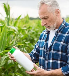 produtor a observar rótulo de produto num campo de milho